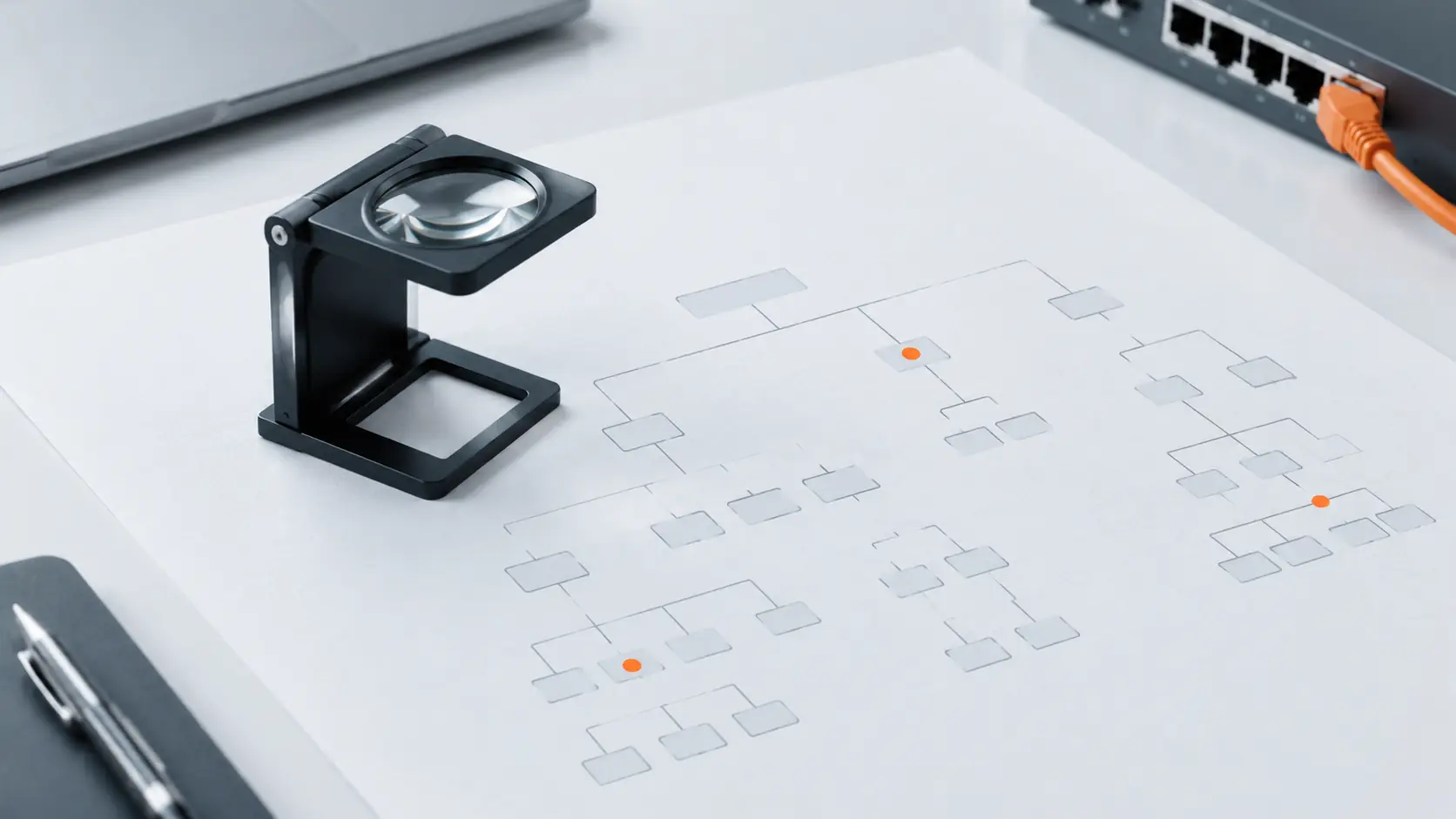 A magnifying loupe resting on a printed site-structure diagram of boxes and lines, three boxes marked with orange dots.